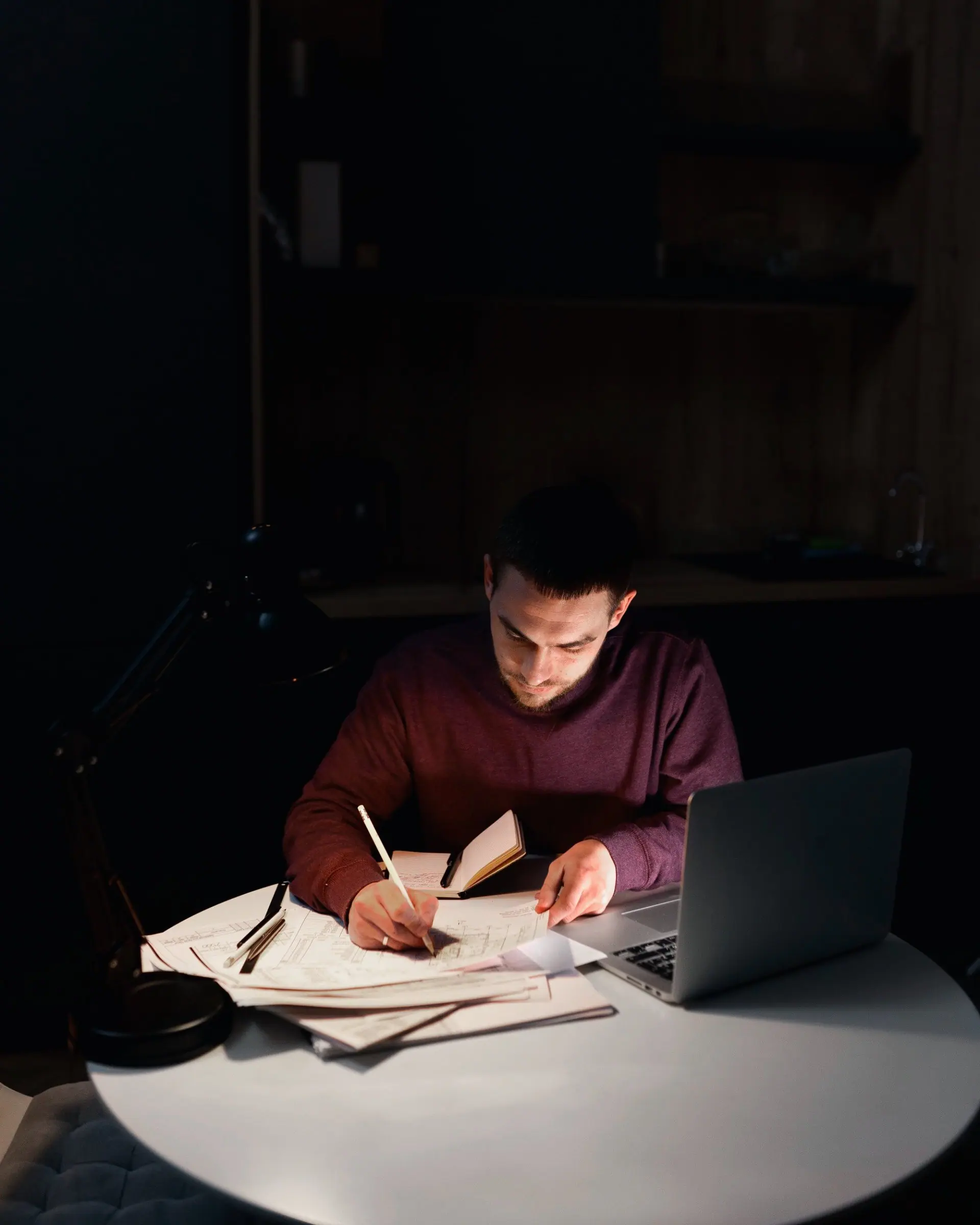 A writer working through notes by lamplight