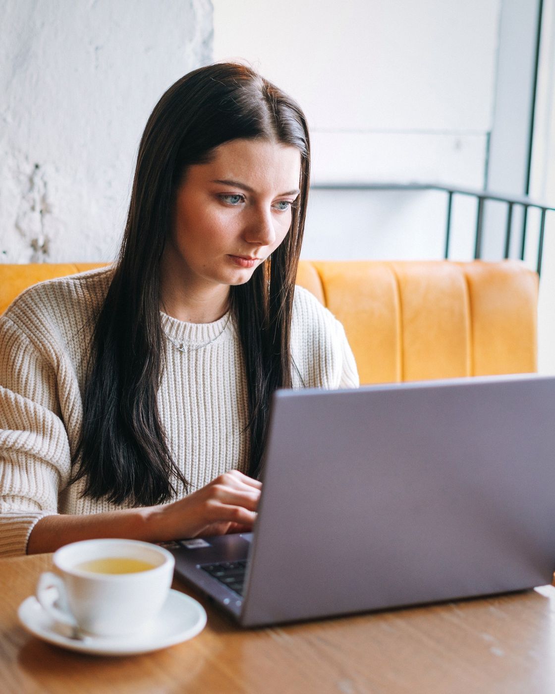 Hands typing on a laptop keyboard beside a cup of coffee