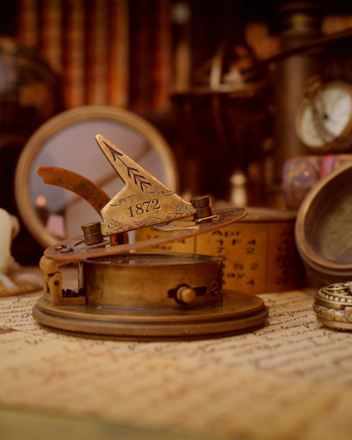 A vintage brass sundial and compass resting on a faded antique map