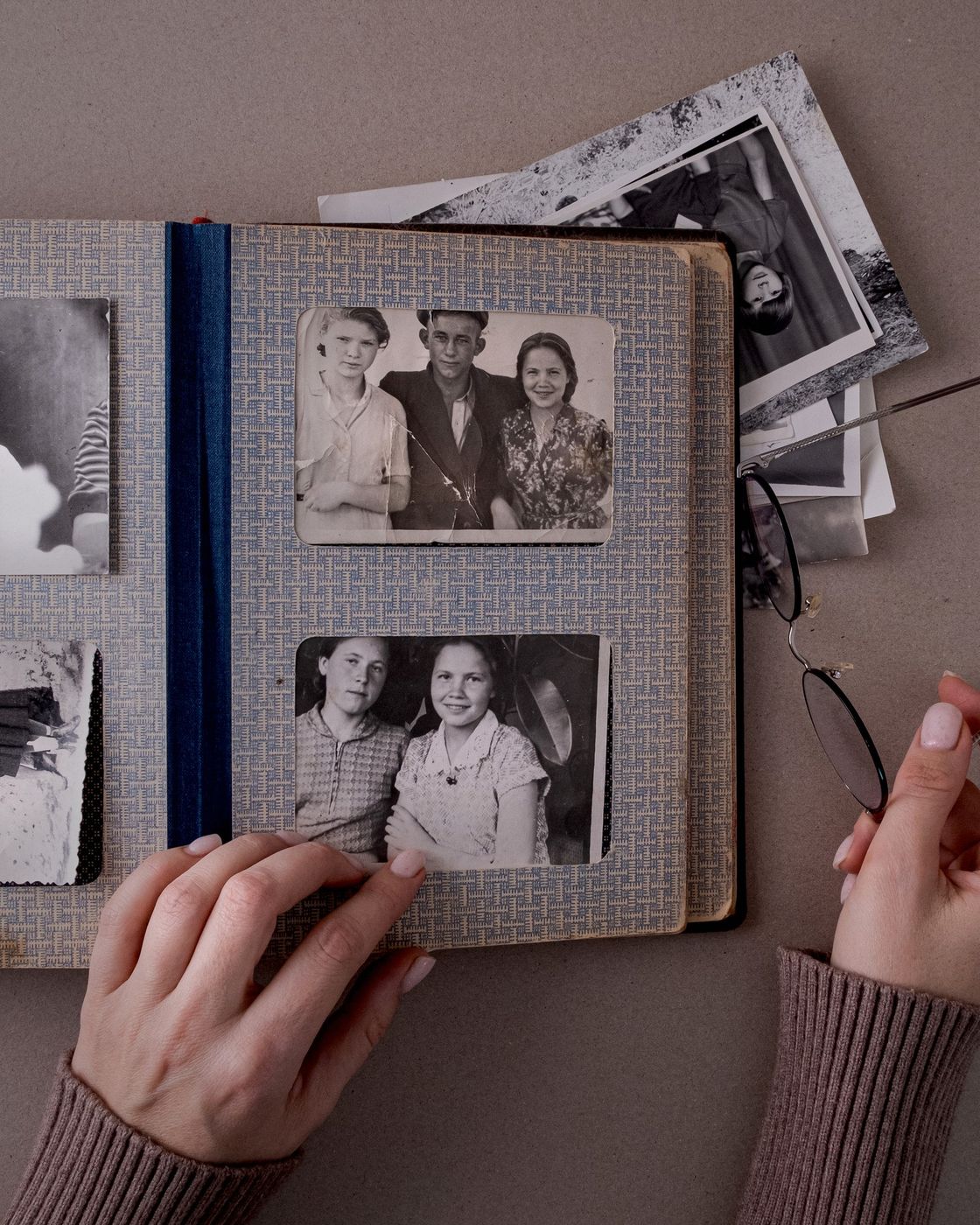 Hands paging through an old photo album of black-and-white family photographs