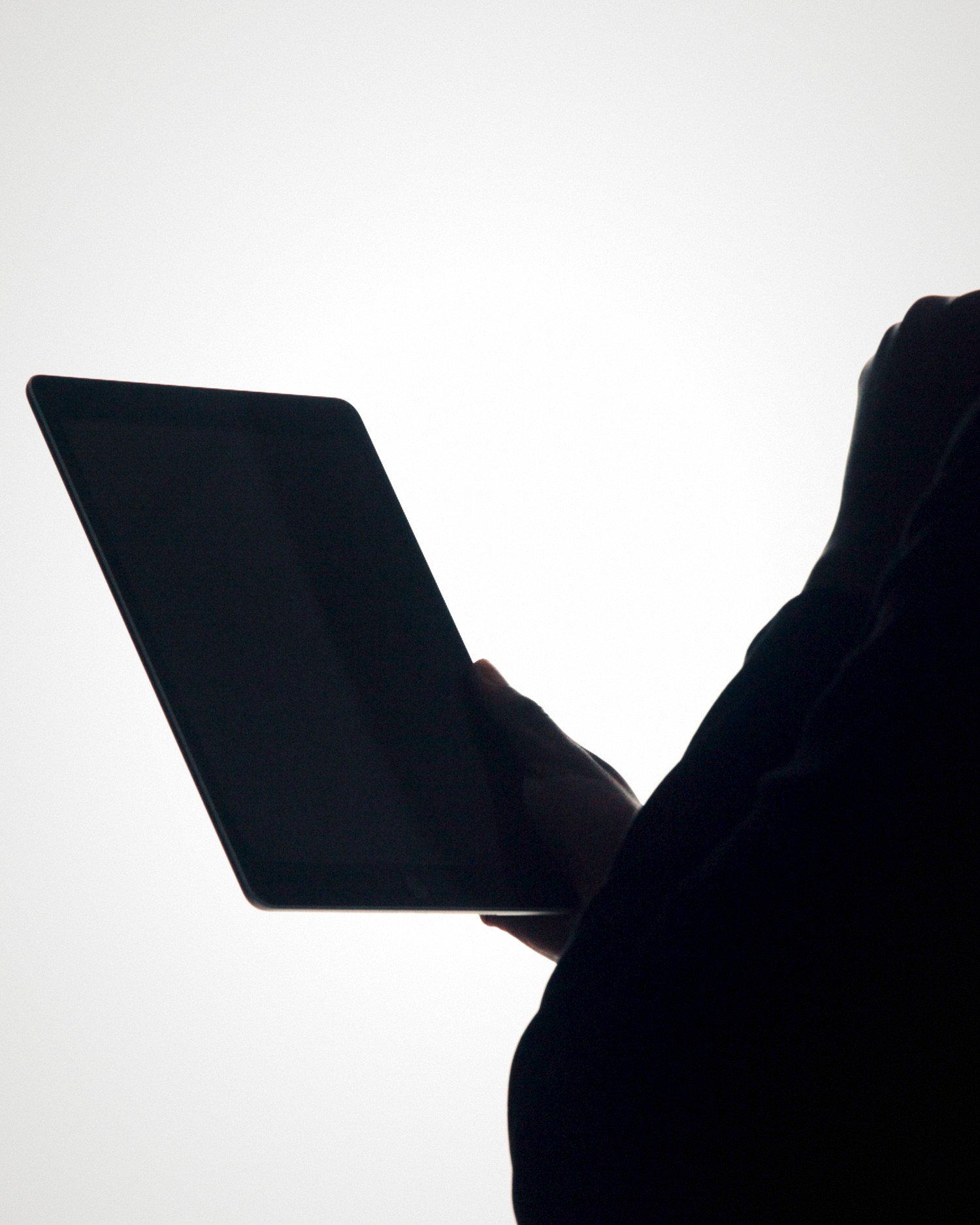 The silhouette of a person working thoughtfully on a digital tablet