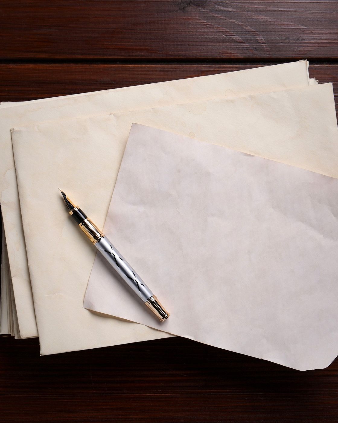 A vintage fountain pen resting on a neatly stacked manuscript