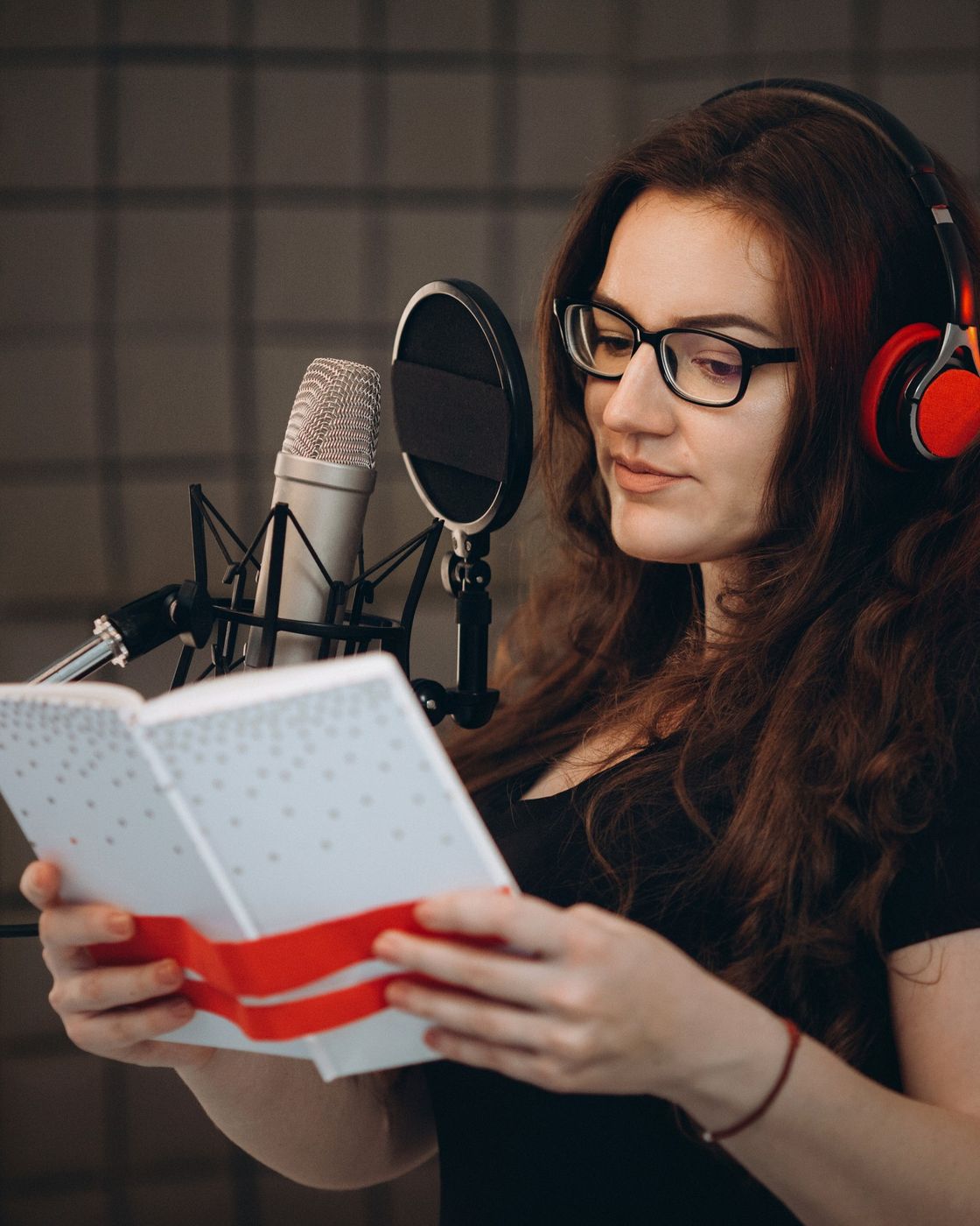 A narrator reading a script into a studio microphone