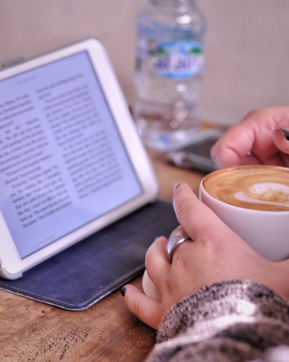 A reader with a tablet displaying an eBook beside a cup of coffee