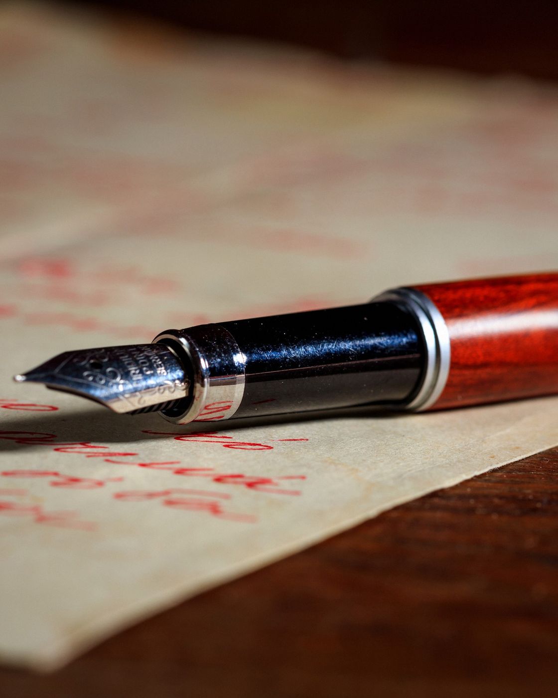 A fountain pen resting on a page of handwritten red-ink edits