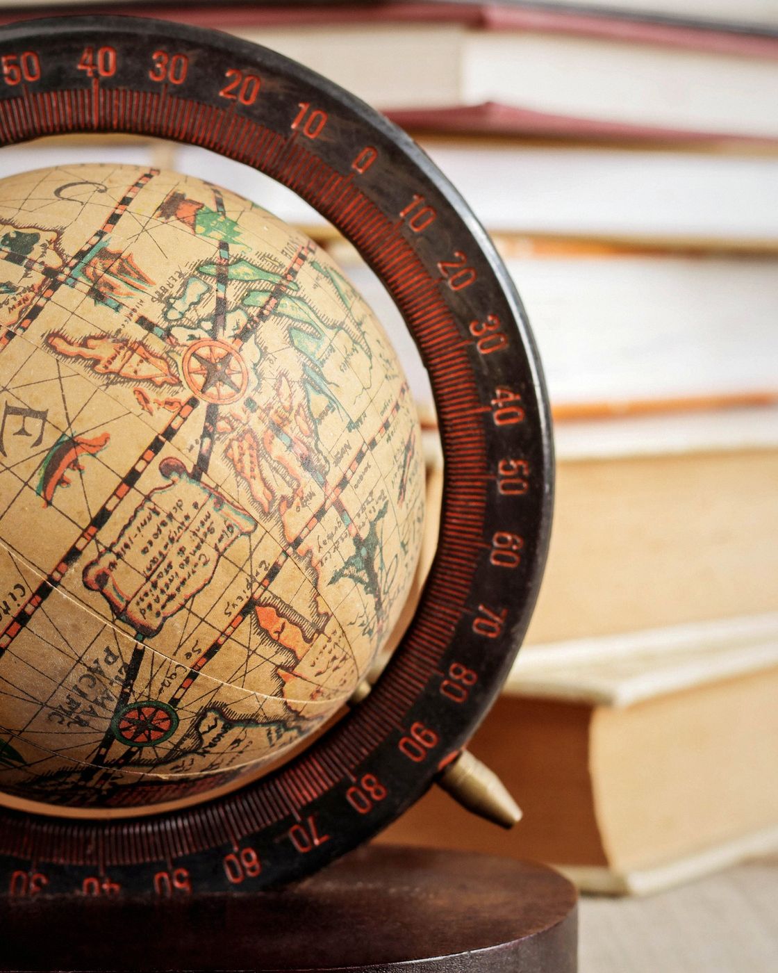 A vintage globe surrounded by stacked antique books